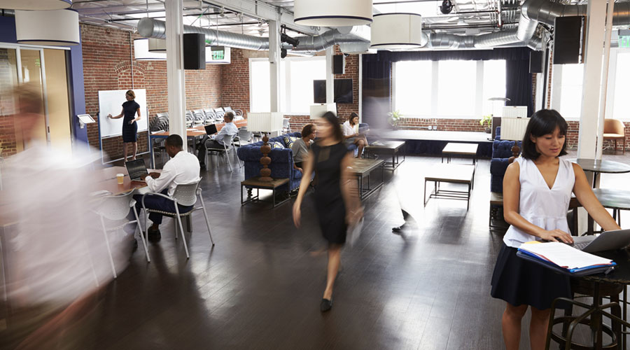 female walking in office with other workers on computers